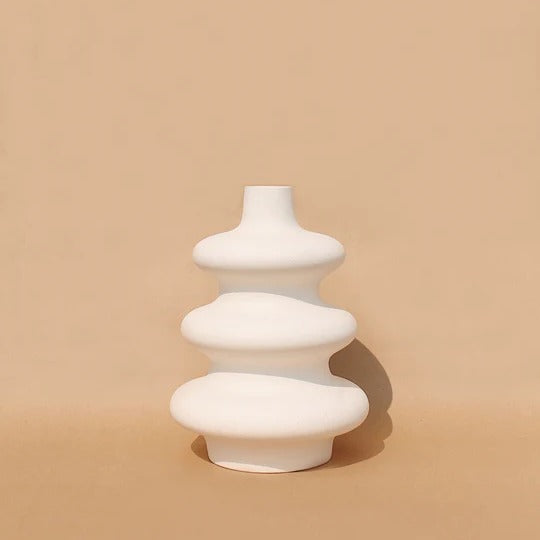 A white, contour-shaped ceramic vase on a plain background.
