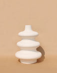 A white, contour-shaped ceramic vase on a plain background.