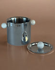 Silver ice bucket with marble handles and base on a brown background