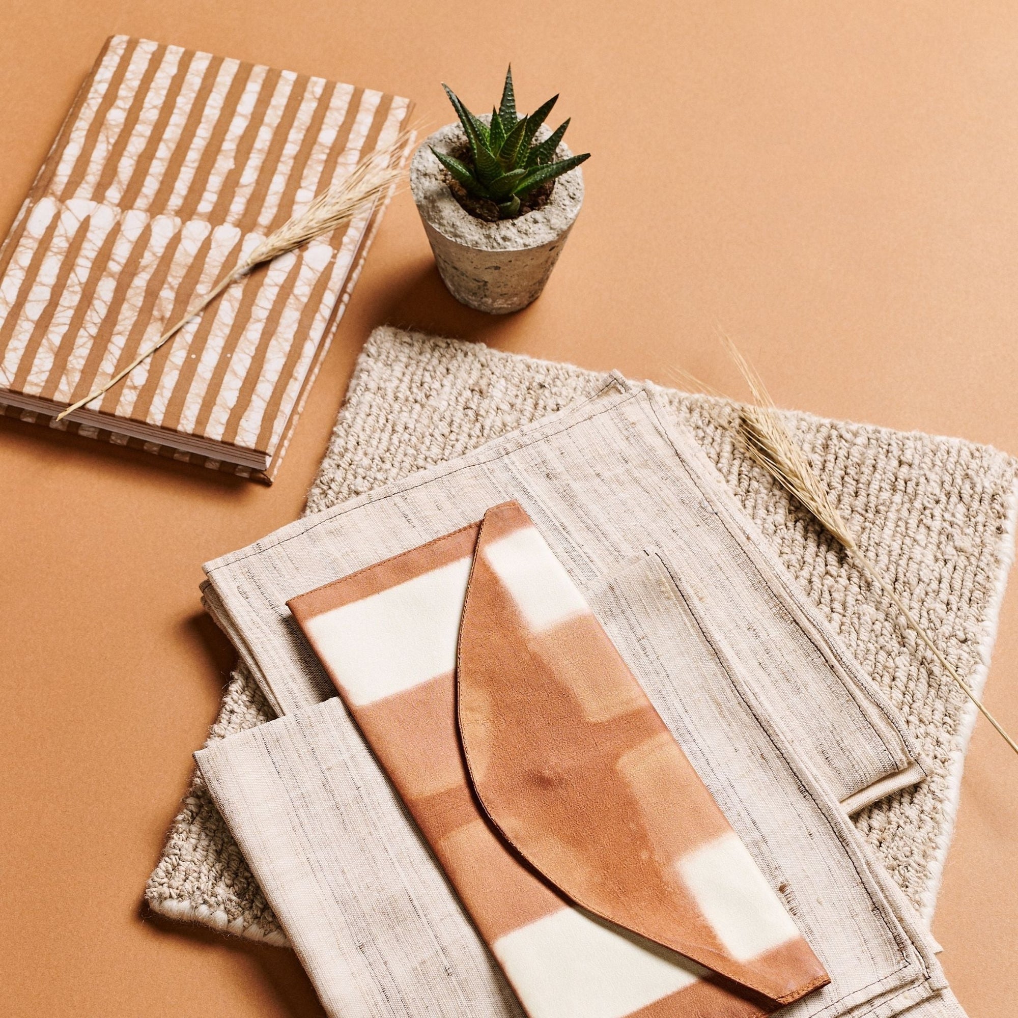 Notebooks and a small potted plant on a textured surface with a brown background