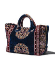 Decorative fabric carpet bag with intricate patterns on a white background