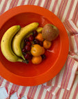 A red and white cotton tablecloth with a bowl of fruit on top
