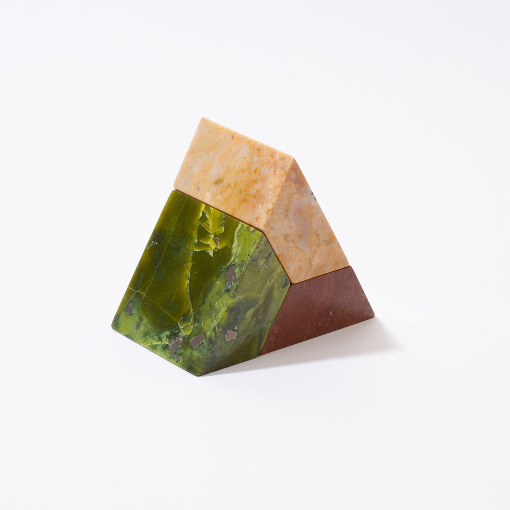 A triangular sculptural puzzle made of three pieces of different colored gemstones, arranged in a triangular formation on a white background.