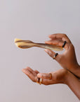 A pair of hands holding a horn butter and cheese spreader with a light beige color