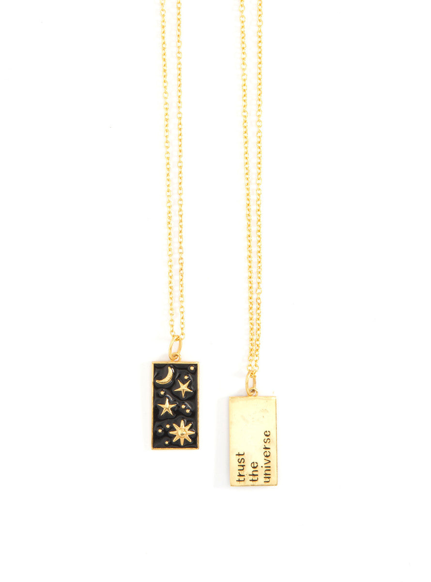 A gold-plated pendant necklace with a rectangular black enamel pendant featuring a white star and moon pattern, connected to a chain by a small gold-plated bar.