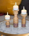 Three wooden candle holders with candles on a marble surface