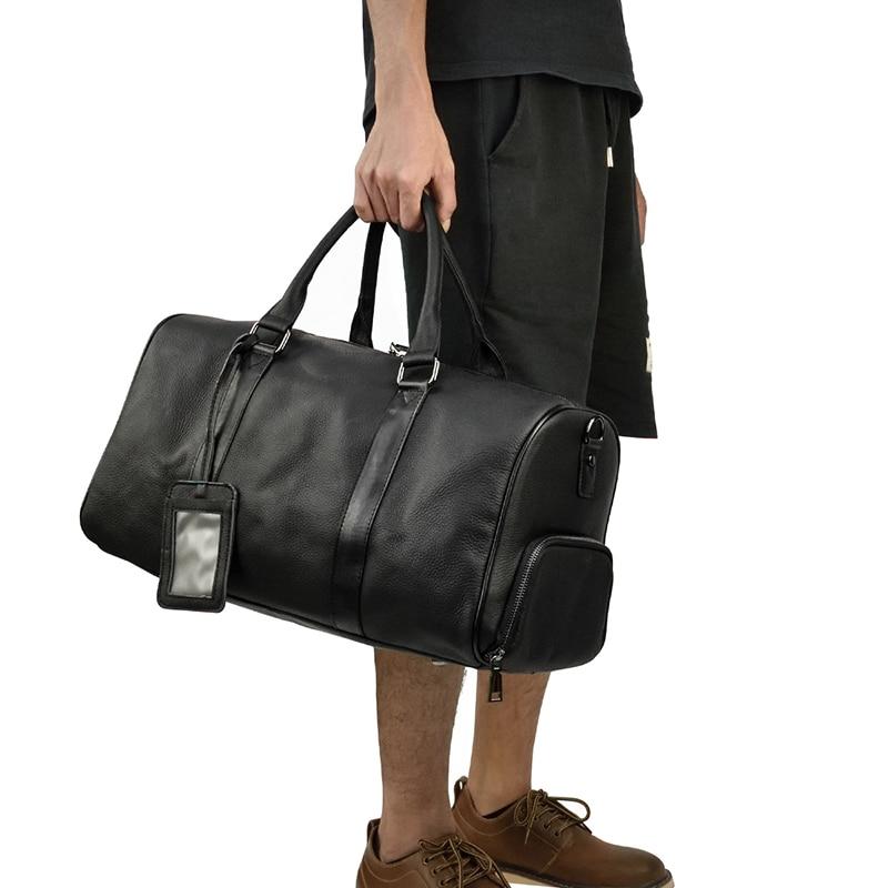 A person carrying a black leather weekender with a leather handle and visible stitching details with a white background.