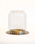 Clear glass lantern with brass base on a white background