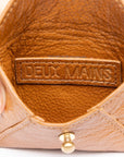 Brown leather product with 'DEUX MAINS' label held by a hand on a white background