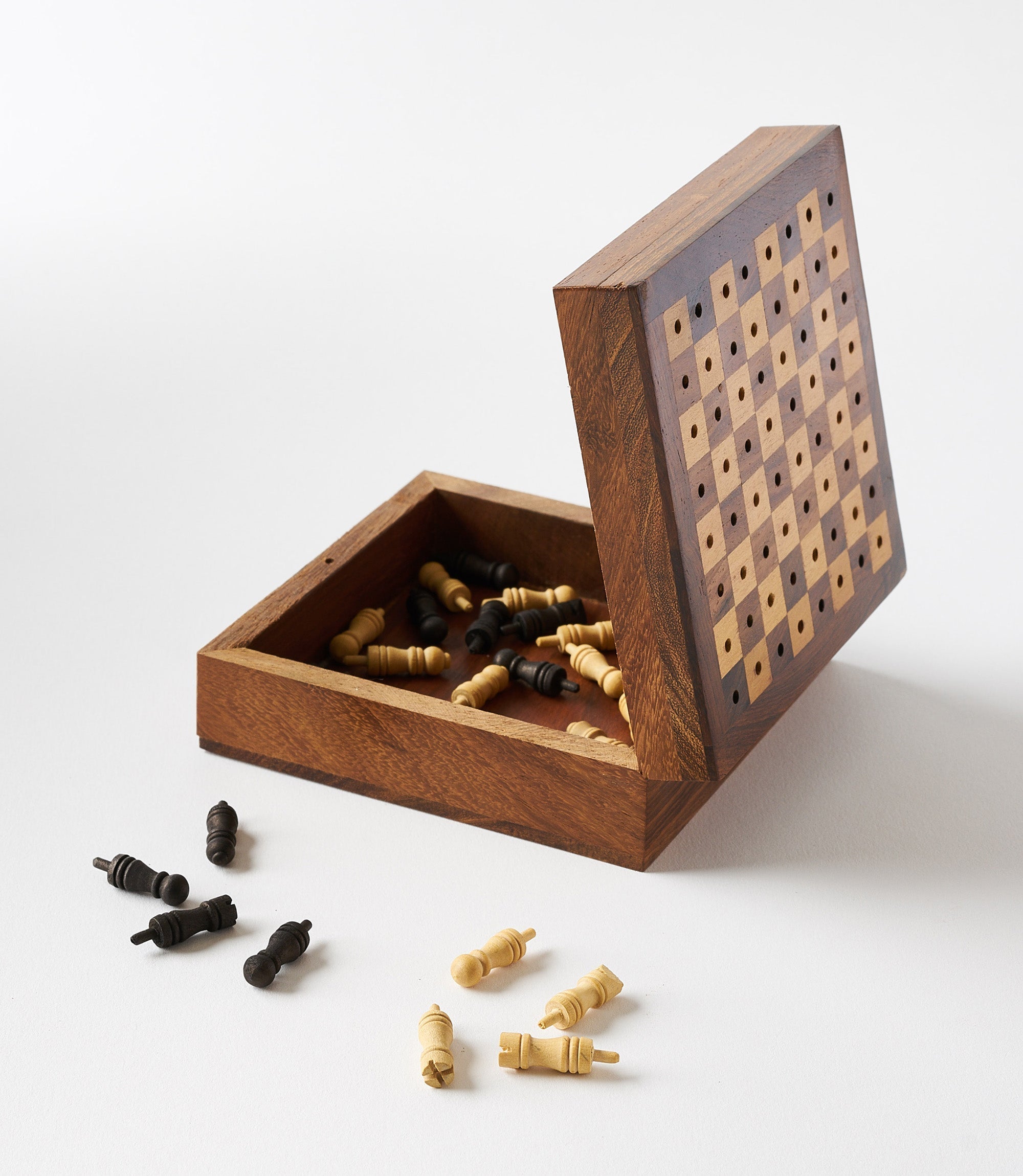 A portable wooden chess game with pieces carved from Indian rosewood, displayed on a white and brown checkered board opened up with the pieces inside.