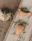 Three ceramic planters shaped like birds on a wooden surface.