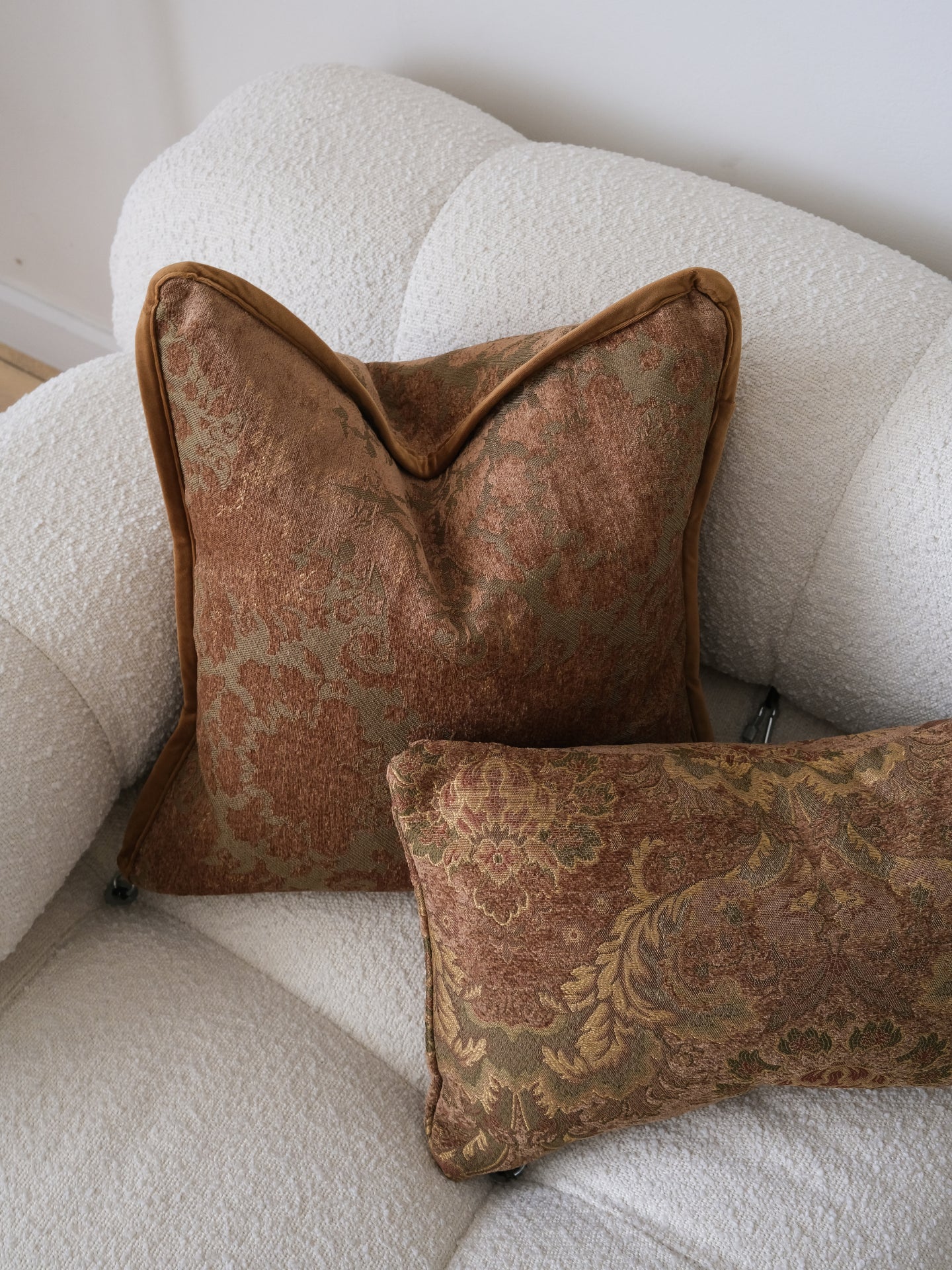 Two brown patterned pillows on a beige sofa