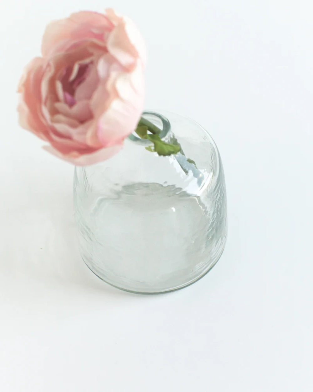 Clear glass vase with a pink rose on a white background