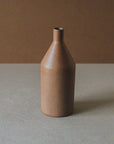 A brown ceramic vase with a narrow neck and a rounded body, placed against a neutral background.