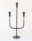 A black iron candelabra with a sturdy weighted base and three arms for holding candles.