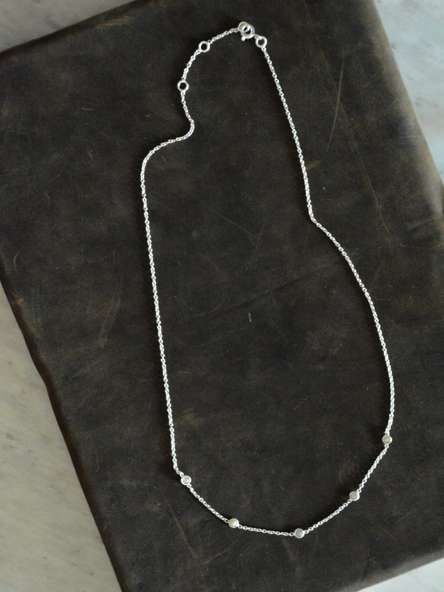 A sterling silver choker necklace with freshwater pearls layered throughout, measuring 16 inches in length displayed on a black table.