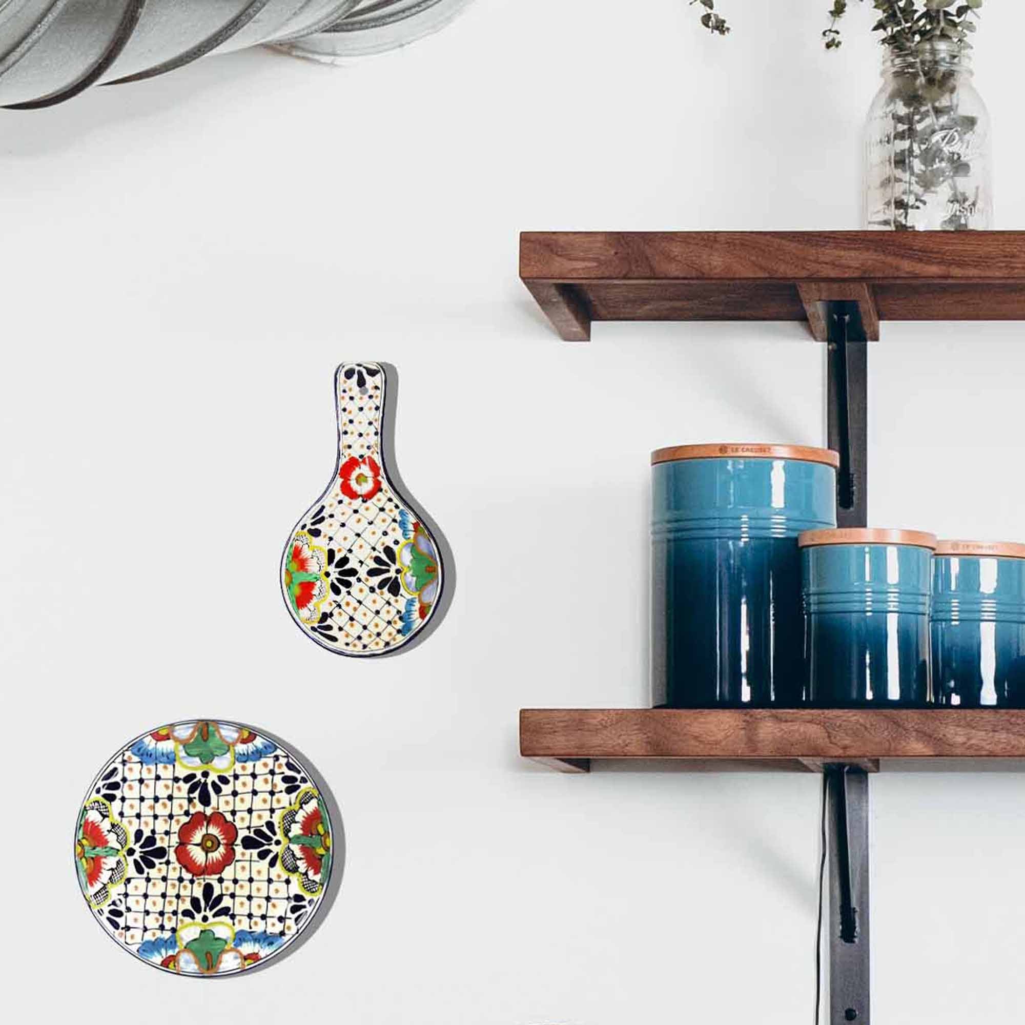 A multicolored, handmade pottery spoon rest hanging on a wall