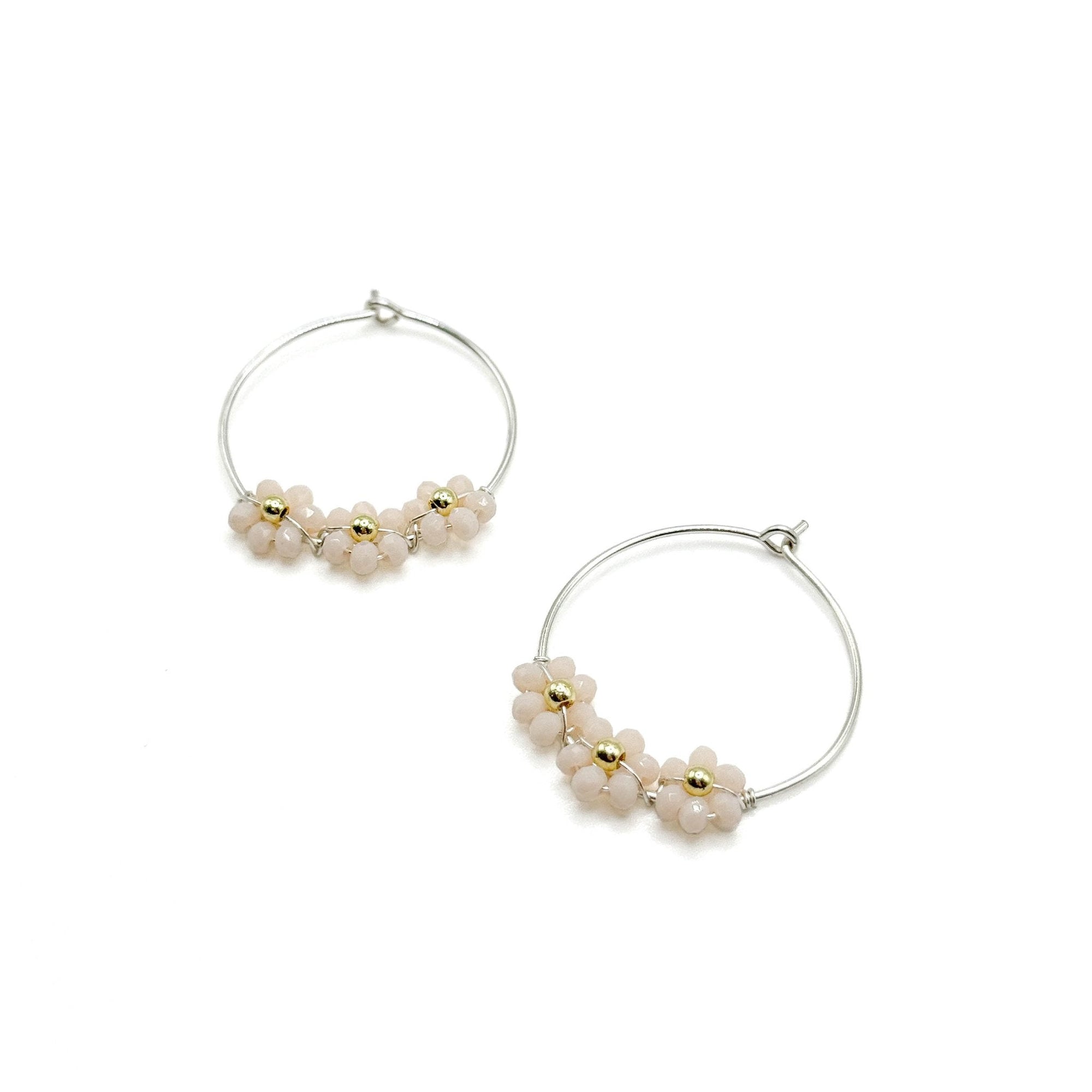 One inch silver plated wire hoops with a hook and loop closure hold 3 white crystal flowers with gold bead centers.