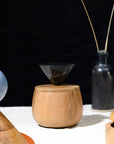 Wooden container with a lid and a small funnel on top, set against a black background.