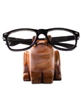 Wooden frog glasses holder with black-framed glasses on a white background