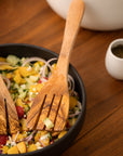 A pair of olive wood spatula forks scooping a salad