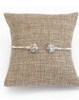A lotus cuff bracelet with a matte finish displayed on a burlap cushion.