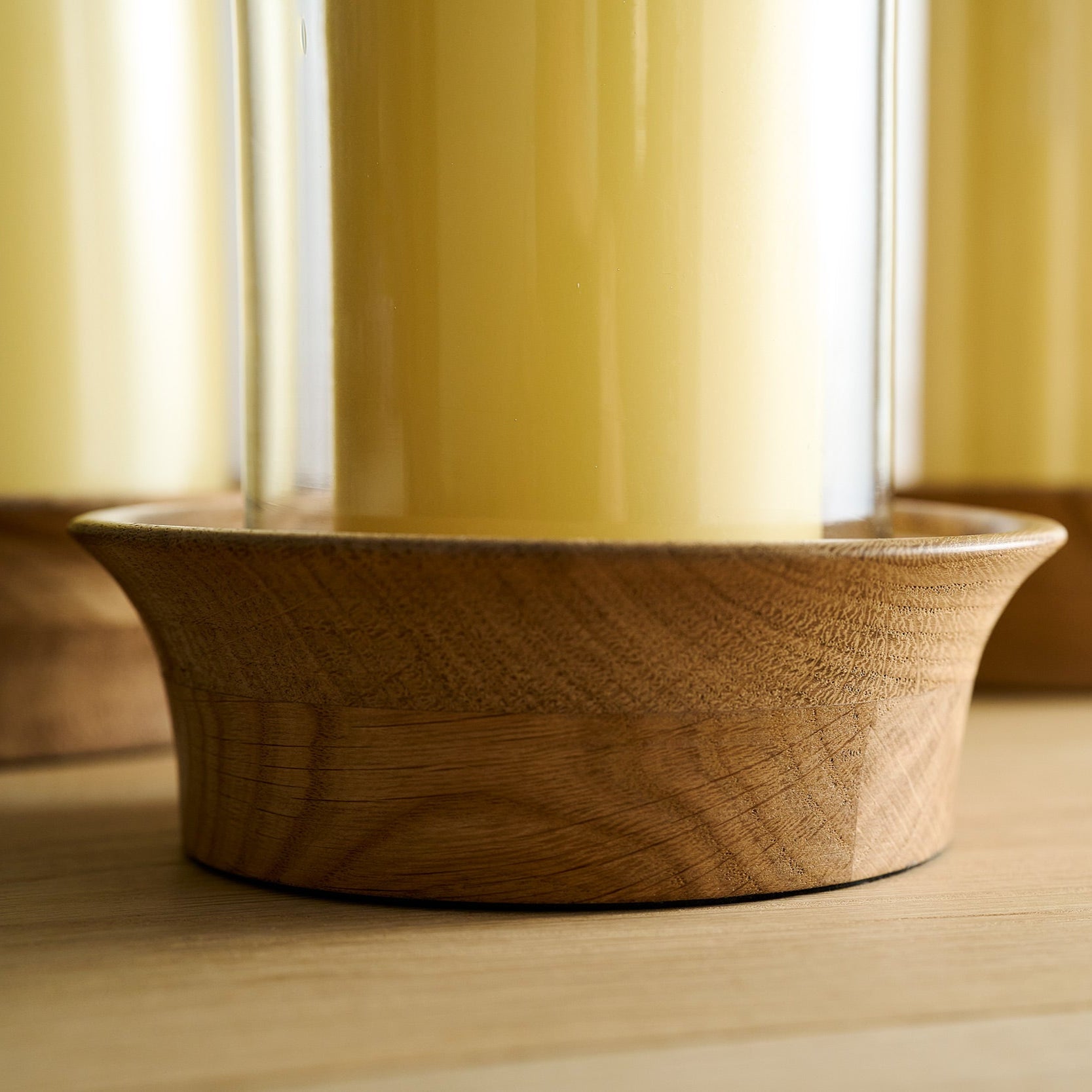 Wooden candle holder on a wooden surface with a soy wax candle on the candle holder