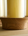 Wooden candle holder on a wooden surface with a soy wax candle on the candle holder