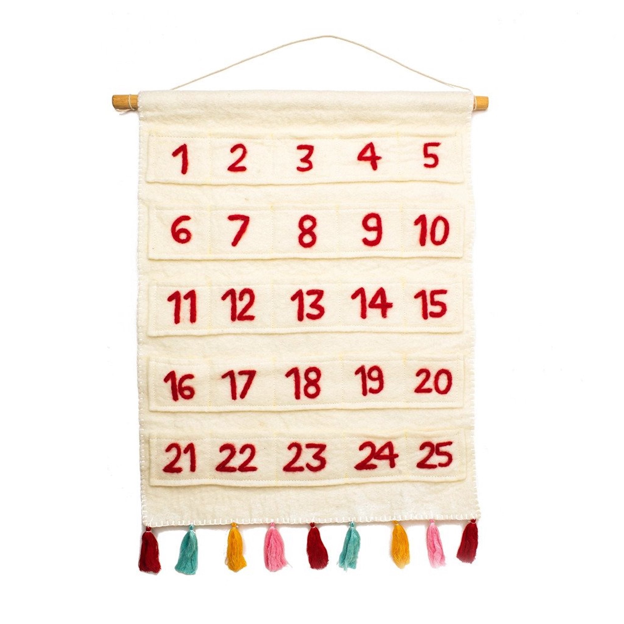 A beige felt advent calendar with red felt numbers from 1 to 25 and colorful cotton tassels hanging on a wooden dowel