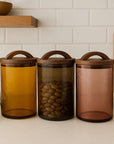 Three glass canisters with wooden lids on a kitchen counter.