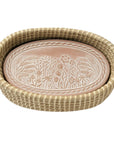 Decorative tray with floral pattern warming stone inside a woven basket on a white background