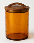 Amber glass jar with a wooden lid on a white background