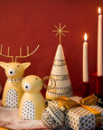 Decorative Christmas scene with reindeer, tree, and presents on a red background