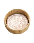 A whitewashed terracotta bread warmer with a birds of a feather design, placed inside a handwoven kaisa grass basket with palm wrap detail.