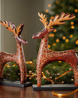 Decorative reindeer figurines on a wooden surface with a festive background.