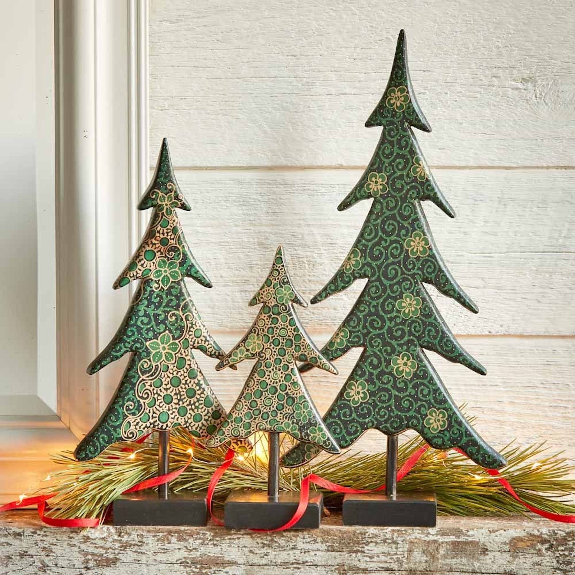 Decorative Christmas trees with green patterns on a wooden surface