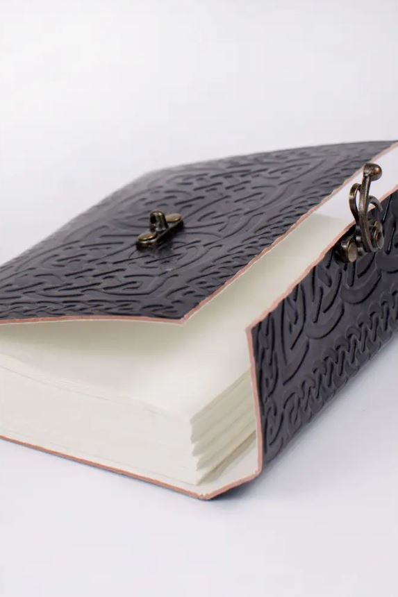 Handmade leather-bound book with embossed design on a white background