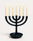 Black menorah with six lit candles on a white background
