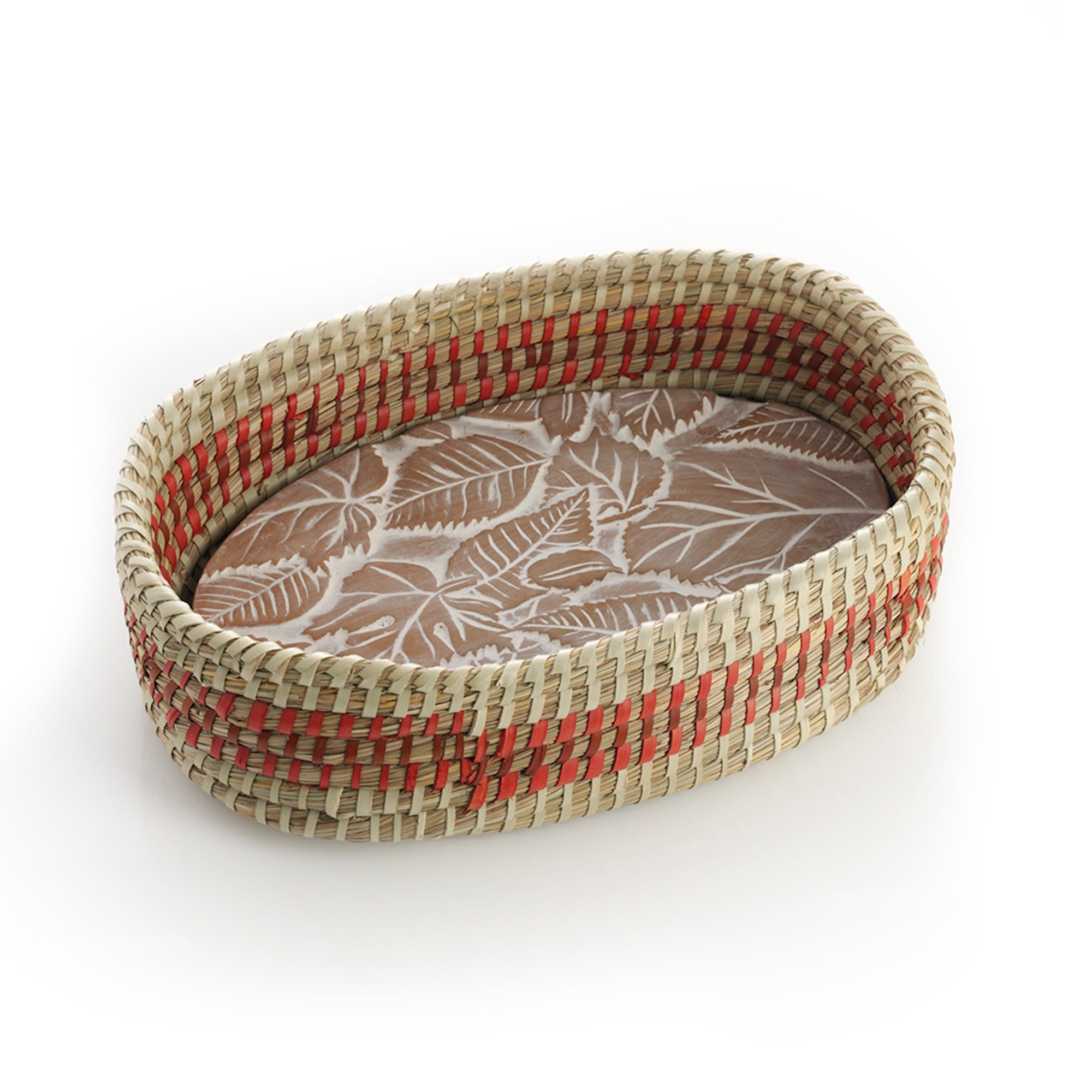 An oval terracotta bread warmer with a falling leaves design, featuring a handwoven kaisa grass basket with red dyed palm wrap detail.