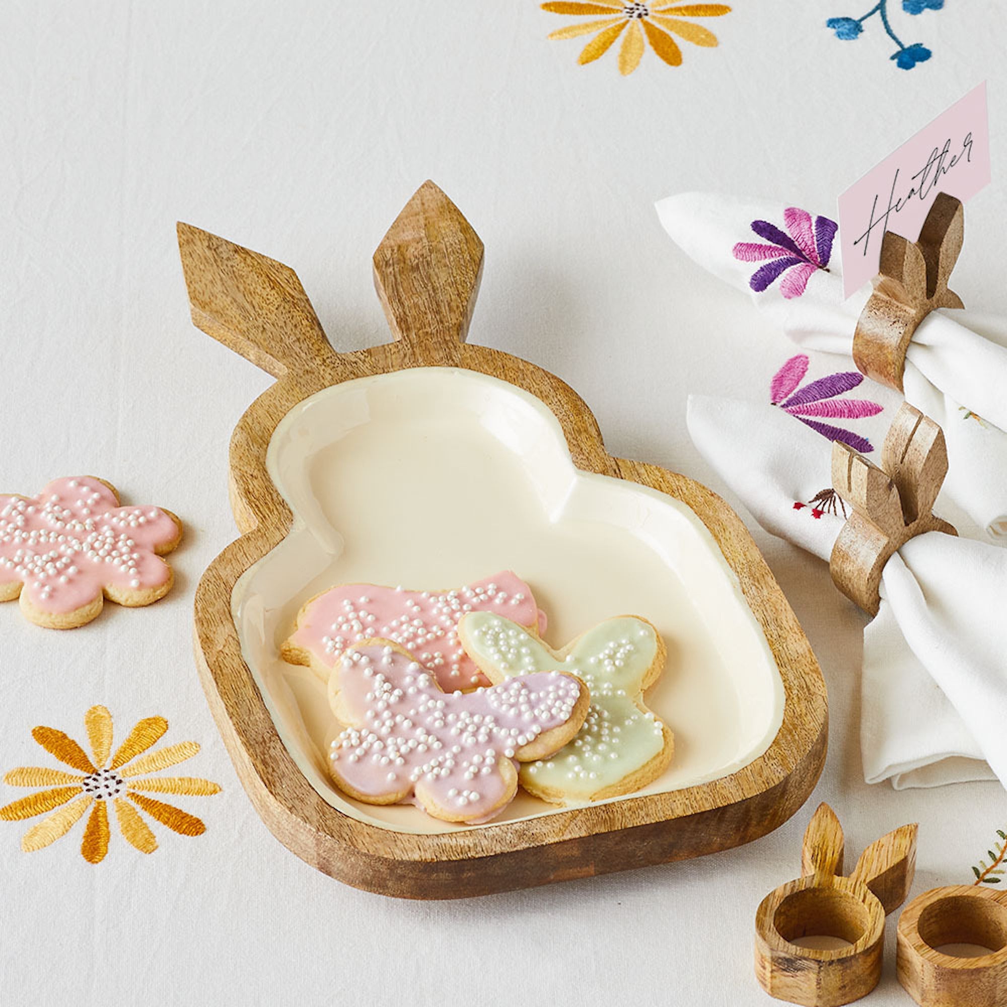A rabbit-shaped serving tray made of wood holding three cookies