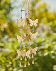 Decorative wind chime with butterflies and beads against a blurred green background