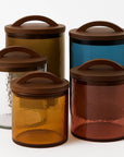 Set of glass canisters with brown lids on a white background