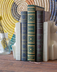 Two carved stone cat bookends holding three books together on a wooden table