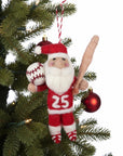 Decorative ornament of a Santa Claus character holding a baseball and bat, hanging on a Christmas tree.