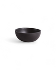 A small, black smooth ceramic bowl against a plain background
