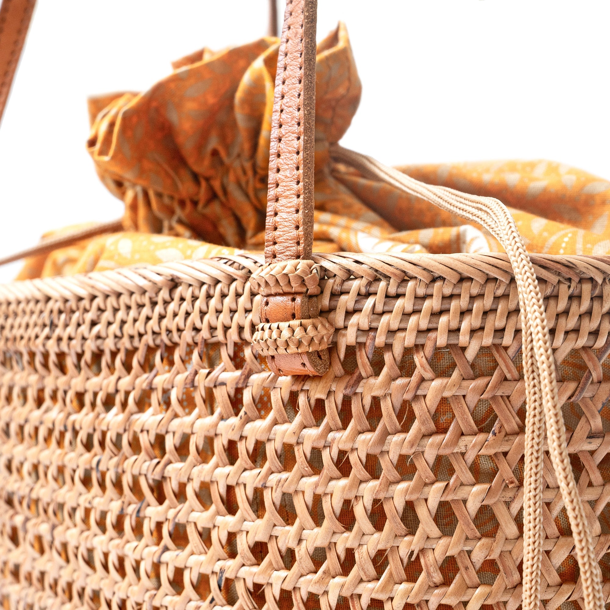 Up close of a brown rattan mesh tote shopper bag with shoulder straps and a drawstring top closure.