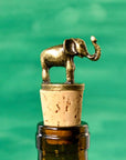 A brass elephant wine bottle stopper sitting atop corks on a bottle of wine.