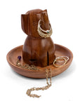 A carved wooden elephant-shaped jewelry stand and tray on a white background, holding gold rings and chains.