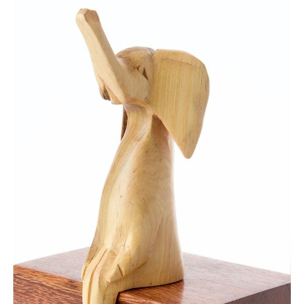 A wooden elephant sculpture perched on a ledge, with a subtle wood grain finish