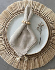 A beige wooden napkin ring holding together a napkin on a plate